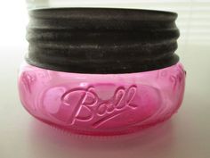 three jars with black and pink lids sitting on top of a white table next to each other