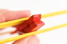 a person holding two yellow pencils in their left hand and one red pencil in the other