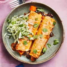 two enchiladas on a green plate with black beans and coleslaw