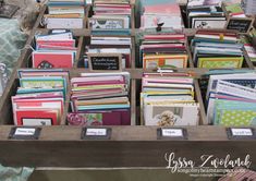 many different types of cards and envelopes are in a wooden box on the table