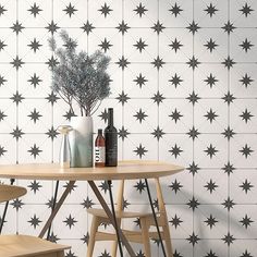 a table with two chairs and a vase on it next to a wall that has black stars