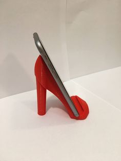 a cell phone sitting on top of a red shoe shaped stand with a silver device sticking out of it