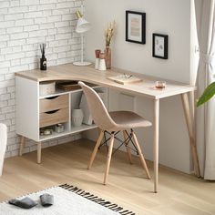 a desk with two chairs next to it in front of a white brick wall and wooden floor