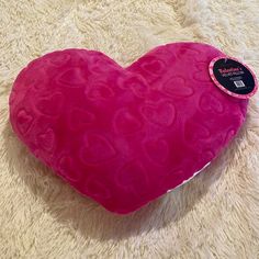 a pink heart shaped pillow sitting on top of a white carpet