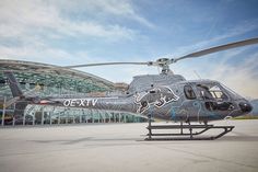 a helicopter sitting on top of an airport tarmac next to a large glass building