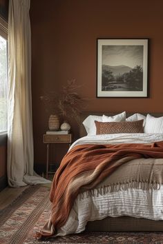 a bedroom with a large bed covered in blankets and throw pillows, along with a painting on the wall