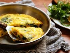 an omelet with spinach and cheese is in a pan on the table