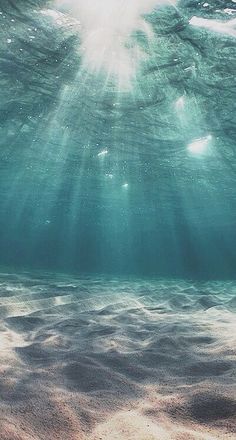 the sun shines through the water as it floats above the sand and sea floor