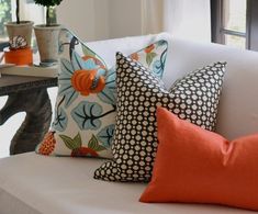 pillows on a white couch in front of a table with potted plants and vases