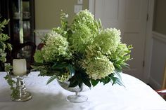 two vases filled with flowers sitting on top of a white tablecloth covered table