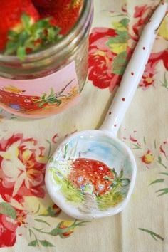 a spoon sitting on top of a table next to a jar filled with strawberries