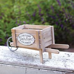 a miniature wooden wheelbarrow with a sign on it