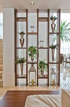 a living room filled with lots of furniture next to a stair case covered in potted plants