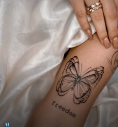 a woman's arm with a butterfly tattoo on it and the words freedom written in cursive writing