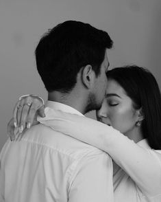 black and white photograph of a couple embracing each other in front of a gray background