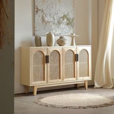 a wooden cabinet with two vases on top and a rug in front of it