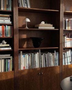 a bookshelf filled with lots of books next to a lamp