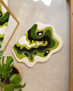 a green and black rug sitting on top of a floor next to a potted plant