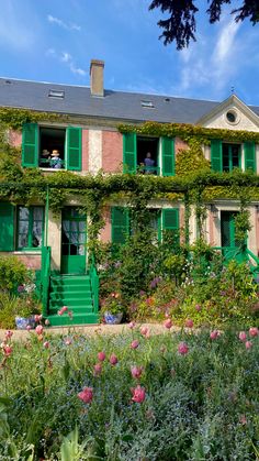 an old house with green shutters and flowers