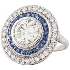 Contemporary target ring composed of platinum with diamonds and sapphires. The center diamond is a round brilliant-cut, 2.75 carats, M color, and VVS2-VSi1 clarity. There are 41 round diamonds totaling 0.75 carats, G-H color and VS2-VS1 clarity. There are 28 calibré-cut sapphires totaling 1.30 carats. The ring is a size 6 1/2. Marked on the inside shank "Plat". Target Ring, Color Change Sapphire, Sapphire Cocktail Ring, Contemporary Ring, Art Deco Engagement, Birthday Ring, Diamond Cocktail Rings, Detailed Ring, Rings Set