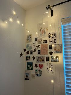 a white wall with many pictures and lights hanging from it's sides on the wall