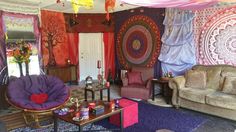 a living room filled with lots of furniture and colorful walls hanging from the ceiling above