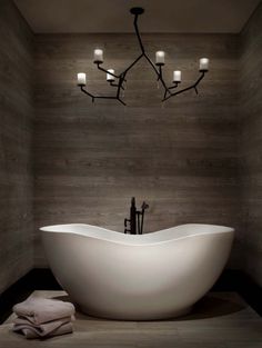 a large white bath tub sitting in a bathroom next to a chandelier with lights on it