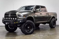 a large gray truck is parked in a room with white walls and black rims