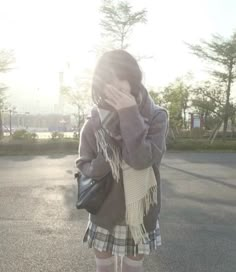 a woman standing in the street with her hand on her face and wearing knee high socks