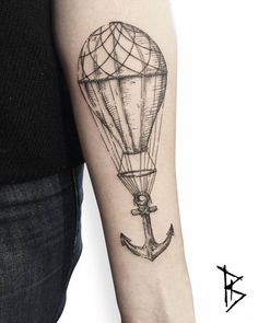 an anchor and hot air balloon tattoo on the left arm, which is drawn in black ink