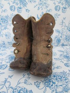 an old pair of brown boots sitting on top of a blue and white table cloth