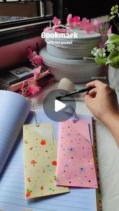 a person is writing on notebooks with flowers in the background and a potted plant next to them