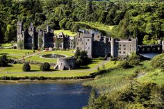 an aerial view of a castle in the middle of a lake surrounded by lush green trees