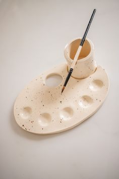 a cup and saucer sitting on top of a plate with a brush in it