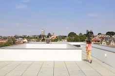 two people standing on the roof of a building with rooftoping tiles and white walls