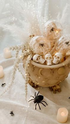 a bowl filled with halloween treats sitting on top of a white table cloth next to candles