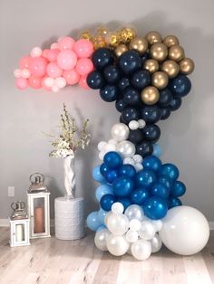 balloons are arranged on the floor in front of a large balloon arch and vase with flowers