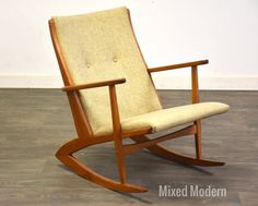 a wooden rocking chair with beige upholstered fabric on the back and seat cushion