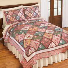 a bed with a pink and green quilt on it