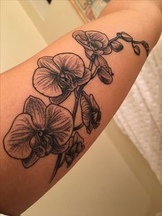 a woman's arm with flowers on it and the words orchids written in black ink