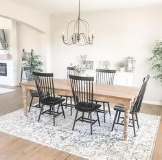 a dining room table with black chairs and a rug