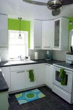 a kitchen with white cabinets and green accents on the walls is pictured in this image