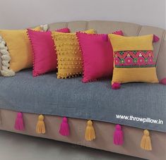 a couch with several pillows and tassels on the back, all in different colors