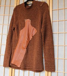 Embrace the fall season with this gorgeous copper-colored upcycled knit sweater, designed to add warmth and style to your wardrobe. The rich hues of copper, brown, and cognac make it the perfect fall essential, bringing a cozy yet chic vibe to any outfit.   Crafted from upcycled knitwear and thoughtfully redesigned with hand-stitched leather scrap on the front and back. The gold pins on the shoulders elevate the design but are removable.  Style it as pictured for an effortlessly chic look, or layer with a blazer, jeans, and sneakers for a casual, yet stylish outfit. This one-of-a-kind piece is not only fashion-forward but also sustainable, making it a standout addition to your wardrobe. Care Instructions: Hand wash. Wipe down leather parts. Do not wring. Hang to drain and dry. Upcycled Knitwear, Reworked Sweater, Leather Scrap, Stocking Fillers For Him, Maternity Nightwear, Copper Brown, Sweater Brown, Blazer Jeans, Stocking Fillers For Her