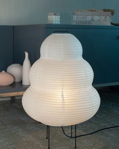 a white lamp sitting on top of a table next to a vase and other items