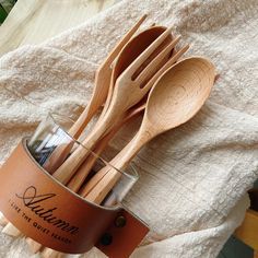 wooden utensils are in a glass cup on a towel with a leather label