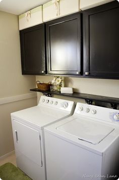 a white washer and dryer sitting in a room next to black cupboards