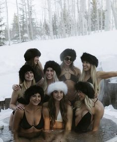 a group of women in bathing suits and fur hats pose for a photo while sitting in a hot tub