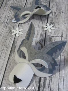 two masks with snowflakes on them sitting on a wooden floor next to each other