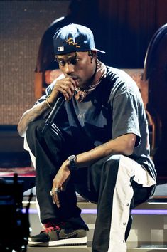 a young man sitting on top of a white bench next to a wooden wall and wearing a hat